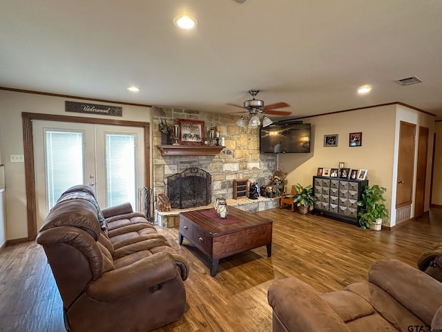 living area with visible vents, a fireplace, crown molding, and wood finished floors