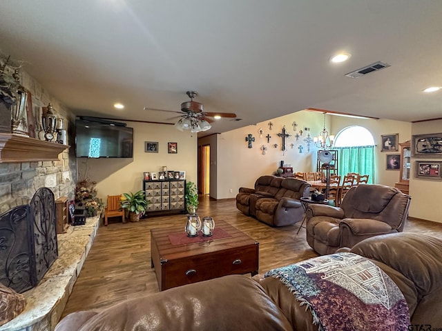 living room featuring visible vents, ceiling fan with notable chandelier, wood finished floors, recessed lighting, and a fireplace