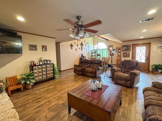 living room with visible vents, ornamental molding, a ceiling fan, wood finished floors, and lofted ceiling