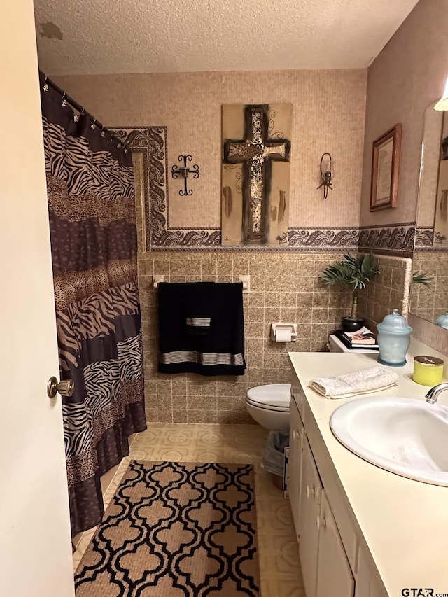 full bath with vanity, a fireplace, a textured ceiling, tile walls, and toilet