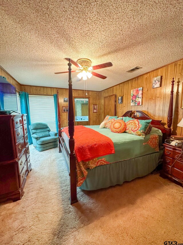 carpeted bedroom featuring wooden walls, visible vents, a textured ceiling, and a ceiling fan