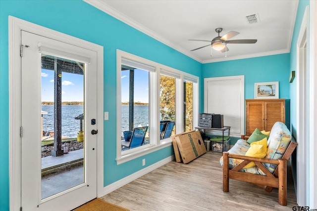 doorway to outside featuring a water view, light hardwood / wood-style flooring, ceiling fan, and crown molding