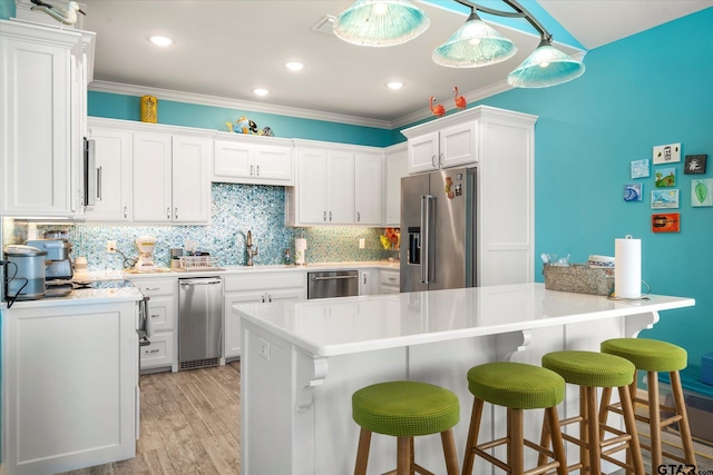 kitchen with white cabinetry, light hardwood / wood-style flooring, decorative light fixtures, and appliances with stainless steel finishes