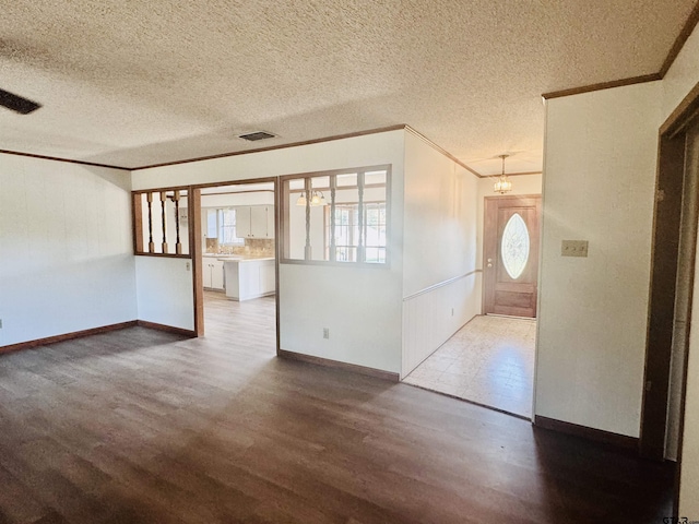 empty room with ornamental molding, a textured ceiling, hardwood / wood-style flooring, and a notable chandelier