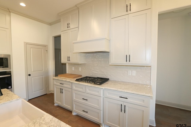 kitchen with built in microwave, tasteful backsplash, white cabinetry, custom range hood, and dark hardwood / wood-style floors