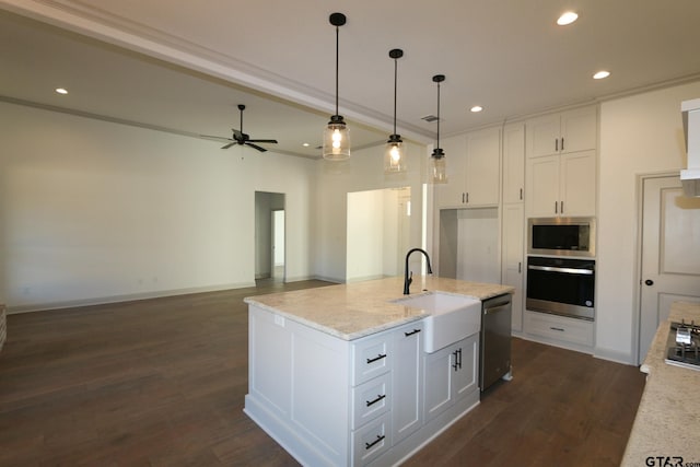 kitchen featuring white cabinets, stainless steel appliances, an island with sink, hanging light fixtures, and light stone counters