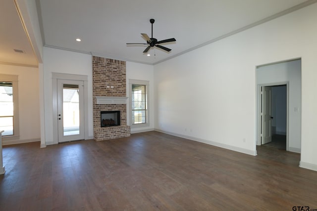 unfurnished living room featuring a brick fireplace, plenty of natural light, dark hardwood / wood-style floors, and ornamental molding