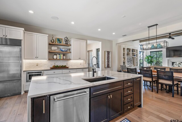 7612 Crosswater, Tyler, TX 75703 - kitchen featuring appliances with stainless steel finishes, a sink, white cabinetry, a kitchen island with sink, and open shelves