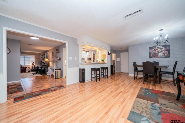 living room with hardwood / wood-style flooring, crown molding, brick wall, and an inviting chandelier