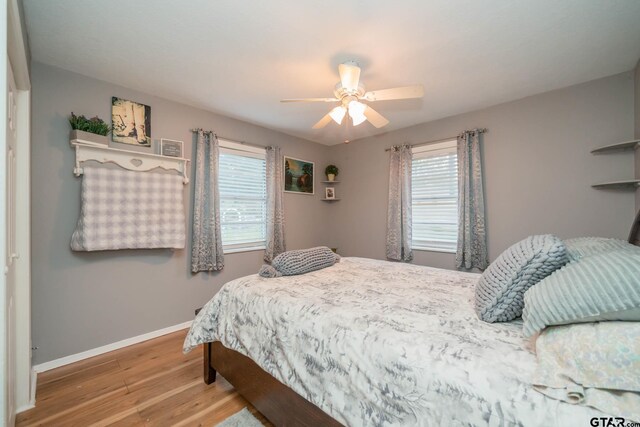 bedroom featuring multiple windows, ceiling fan, and wood-type flooring