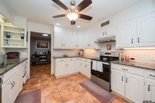 kitchen featuring stainless steel electric range oven, light tile patterned floors, backsplash, dark stone countertops, and white cabinets