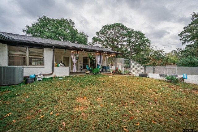 rear view of property with a yard, cooling unit, and a patio