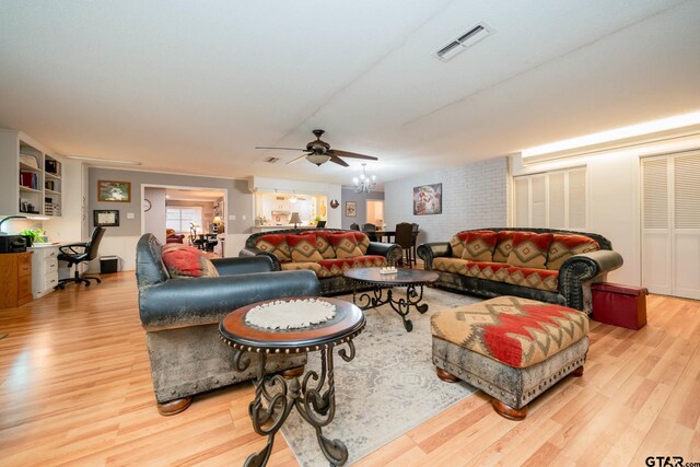 living room featuring ceiling fan with notable chandelier and light wood-type flooring