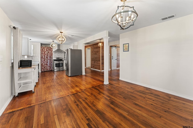 kitchen with stainless steel appliances, a chandelier, wall chimney exhaust hood, and tasteful backsplash