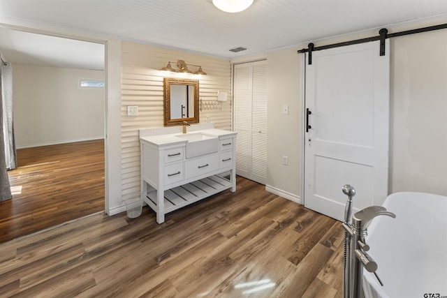 interior space with a barn door, visible vents, dark wood finished floors, and baseboards