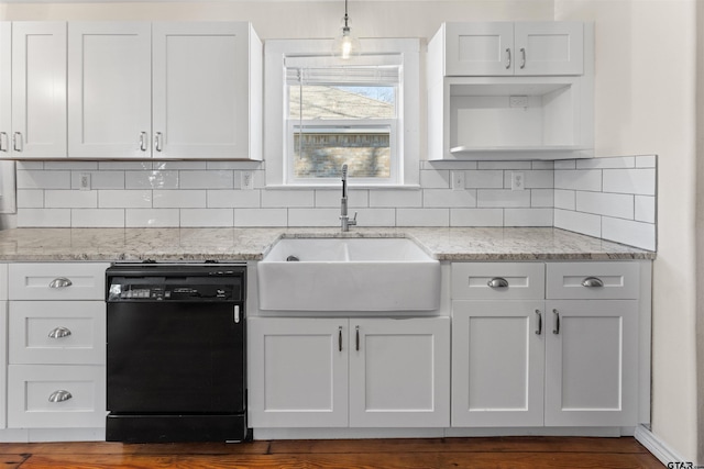 kitchen featuring light stone counters, black dishwasher, a sink, and backsplash