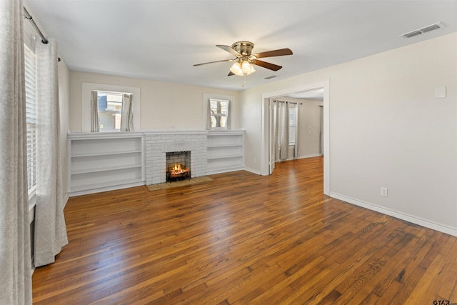 unfurnished living room featuring a fireplace, wood-type flooring, visible vents, a ceiling fan, and baseboards