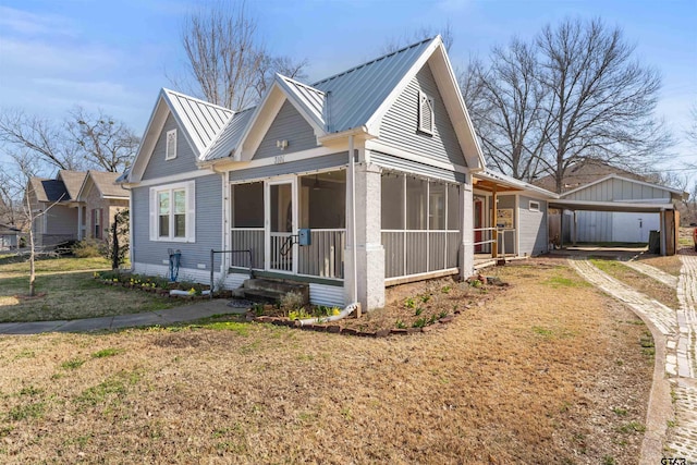 view of front of house with metal roof, a front lawn, a standing seam roof, and a sunroom