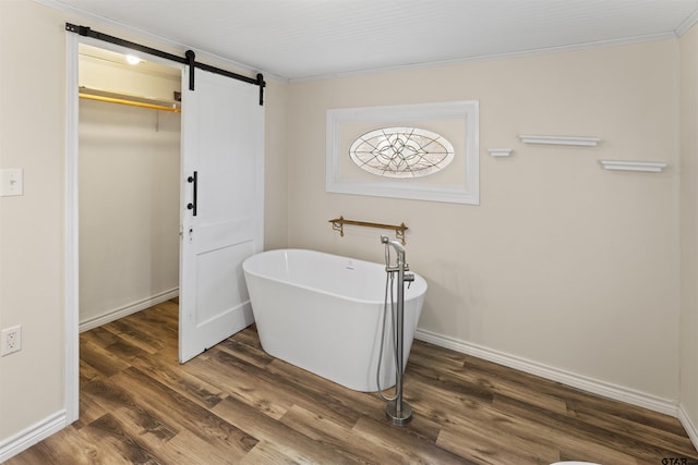 full bath featuring ornamental molding, a freestanding bath, baseboards, and wood finished floors