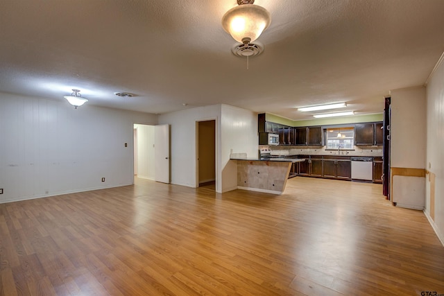 unfurnished living room with light hardwood / wood-style floors, a textured ceiling, and sink