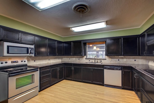 kitchen with crown molding, stainless steel appliances, hanging light fixtures, sink, and light hardwood / wood-style flooring