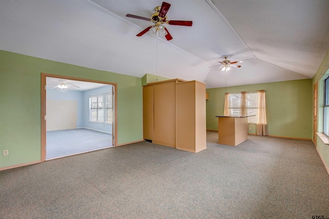 unfurnished living room featuring carpet, plenty of natural light, ceiling fan, and vaulted ceiling