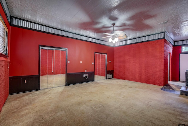 214 County Road 1900, Yantis, TX 75497 - carpeted empty room featuring ceiling fan, brick wall, and a wainscoted wall