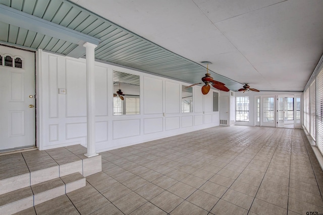 unfurnished sunroom featuring decorative columns, vaulted ceiling, and ceiling fan