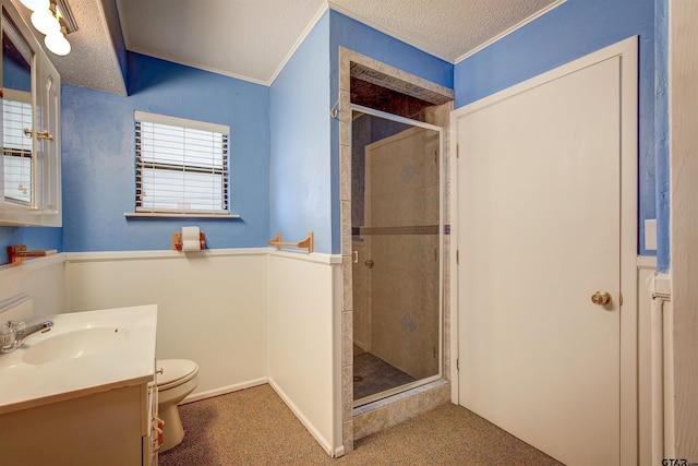 bathroom featuring a shower with door, ornamental molding, a textured ceiling, vanity, and toilet