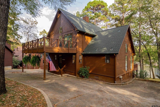 207 S King Laurence Ct, Scroggins, TX 75480 - view of front facade featuring a shingled roof, a chimney, a deck, and concrete driveway