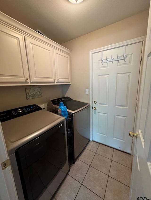 washroom featuring washing machine and dryer, cabinet space, and light tile patterned floors