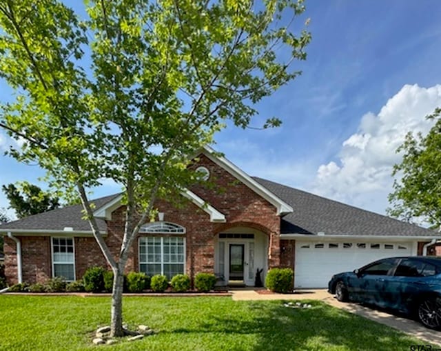 view of front facade with an attached garage, a front lawn, brick siding, and driveway
