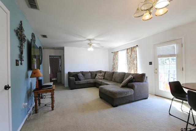 carpeted living room featuring visible vents, plenty of natural light, and ceiling fan with notable chandelier