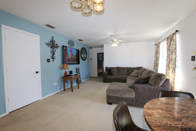 living area featuring ceiling fan with notable chandelier, visible vents, baseboards, and light colored carpet