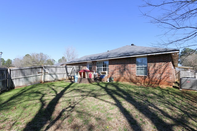 rear view of house with fence, a lawn, and brick siding