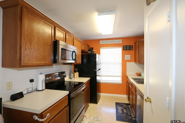 kitchen featuring appliances with stainless steel finishes, brown cabinets, backsplash, and light countertops