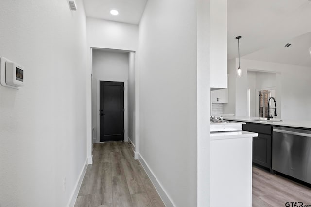 corridor with light hardwood / wood-style floors and sink