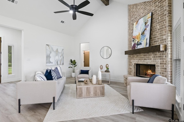 living room featuring a fireplace, high vaulted ceiling, a ceiling fan, wood finished floors, and beamed ceiling