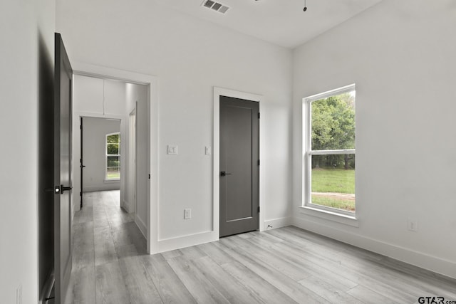 unfurnished bedroom with baseboards, multiple windows, and light wood finished floors