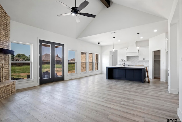 unfurnished living room featuring beam ceiling, high vaulted ceiling, and light hardwood / wood-style floors