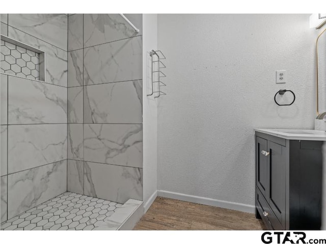 1812 Montrose Dr, Tyler, TX 75701 - bathroom featuring vanity, wood finished floors, tiled shower, and baseboards