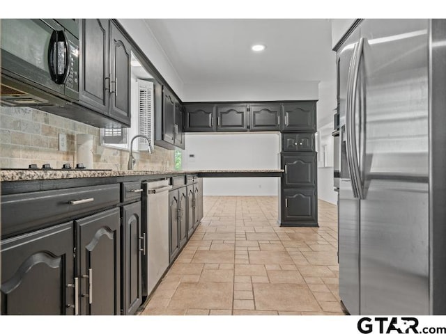 1812 Montrose Dr, Tyler, TX 75701 - kitchen with stainless steel appliances, backsplash, stone tile floors, recessed lighting, and a sink