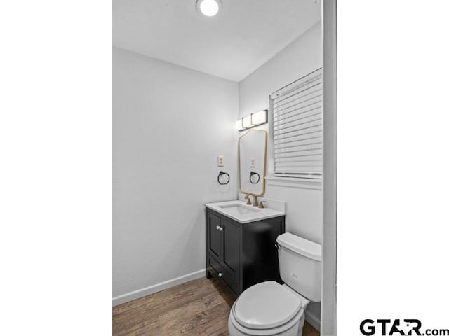 bathroom featuring toilet, wood finished floors, vanity, and baseboards