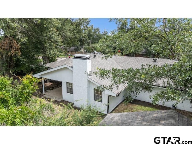 1812 Montrose Dr, Tyler, TX 75701 - view of side of home with roof with shingles, a chimney, and view of scattered trees