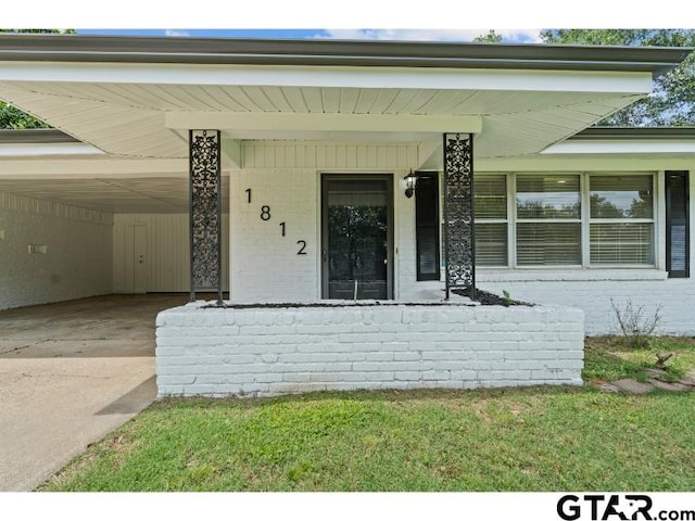 1812 Montrose Dr, Tyler, TX 75701 - view of exterior entry with brick siding, driveway, an attached carport, and a porch