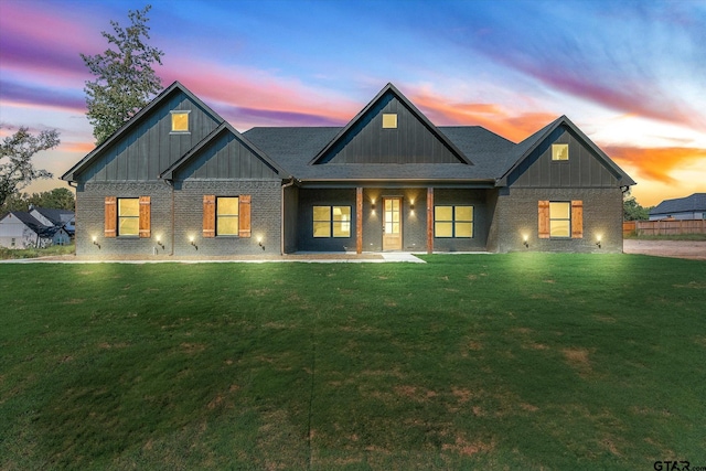 back house at dusk featuring a lawn