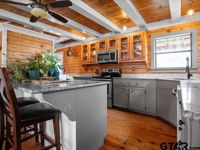 kitchen with sink, stone counters, gray cabinetry, appliances with stainless steel finishes, and beam ceiling