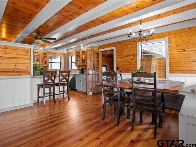 dining space with beamed ceiling, hardwood / wood-style flooring, wooden walls, and wood ceiling