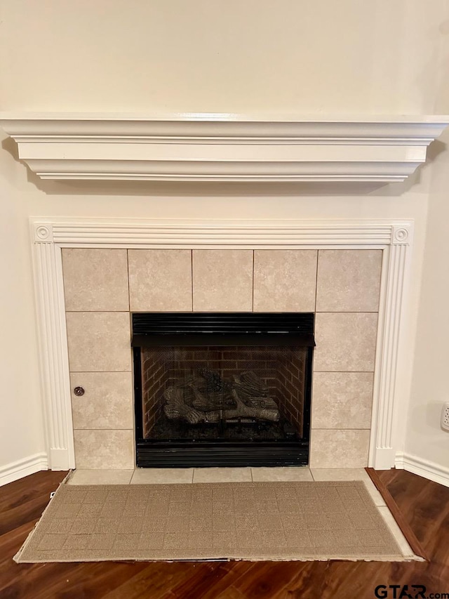 interior details featuring a tiled fireplace and hardwood / wood-style flooring