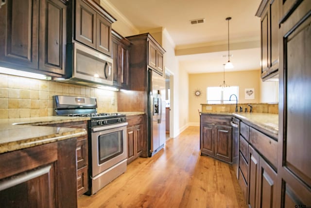 kitchen featuring pendant lighting, sink, light hardwood / wood-style flooring, appliances with stainless steel finishes, and light stone counters